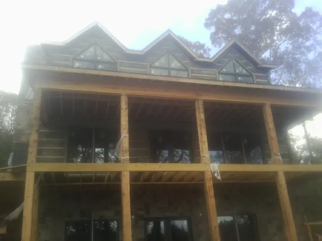 Dormers and porch framing on a large log home under construction — Roof Coating work by our crew in Emerson